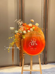 an orange frisbee with flowers in it sitting on a stand