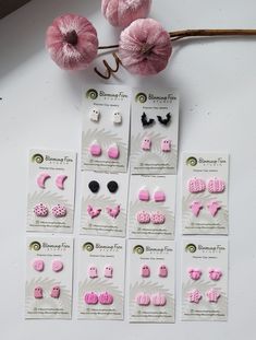 pink and black earrings are on display next to some yarn balls with flowers in the background