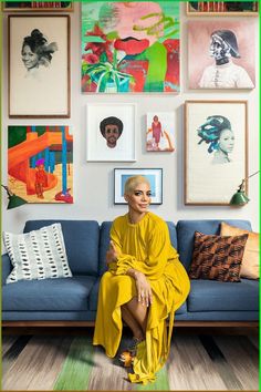 a woman sitting on top of a blue couch in front of pictures hanging on the wall