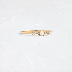 a gold ring with three stones on it, sitting on a white surface and facing the camera