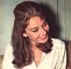 a woman sitting on top of a couch in front of a magazine cover with her hair pulled back