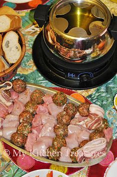 meatballs, bread and other foods on a table with a stove top in the background