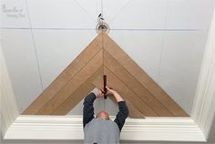 a man is working on the ceiling with wood planks and glueing it together