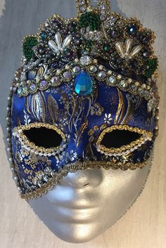 A full face mask suitable to wear or just to have as a subtle but eye-catching decor inclusion, 'Topaz' features an exquisite midnight blue Japanese brocade interwoven with gold and silver-toned highlights and a truly beautiful and ornate tiara which has been heavily hand-glitzed with pearl and 'shot' beading, rhinestones, natural pearls and Swarovski elements.  Each Tiaura Arts piece comes with signed and dated certification detailing its unique title and catalogue number.  To see the full rang Elegant Blue Masquerade Mask For Parties, Elegant Blue Eye Mask For Masquerade, Blue Headpieces For Carnival, Blue Venetian Mask For Carnival, Elegant Crown Headpiece For Masquerade, Blue Venetian Masks For Carnival, Blue Full Face Mask For Masquerade, Elegant Baroque Masquerade Mask For Costume, Elegant Baroque Masquerade Mask For Party