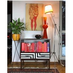 a living room with a book shelf, lamp and pictures on the wall behind it