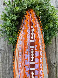 an orange and white football scarf hanging on a wooden fence next to a green bush