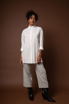 This oversized tunic is draped to be comfortable and flattering on a woman’s body. This style has a beautiful inverted pleat at the back and a unique exaggerated collar. The side slits balance the long length of this elegant and boxy number. Contents: 100% GOTS*-Certified Organic Cotton Natural shell buttons Fit: This style is made to fit oversized; please order the size you normally take. See our sizing guide here. Model is 5'9" and wears a size 6. Care: Machine wash cold. Line dry. A garment's Oversized Asymmetrical Hem Blouse For Daywear, Oversized Blouse With Asymmetrical Hem For Daywear, Chic Tunic With Shirttail Hem For Daywear, Chic Oversized Tunic For Loungewear, Oversized Tunic For Layering, Oversized Tunic With Shirttail Hem, Chic Relaxed Fit Tunic For Daywear, Workwear Blouse With Relaxed Fit And Asymmetrical Hem, Modern Oversized Blouse For Daywear