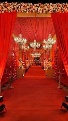 an aisle decorated with red drapes and chandeliers