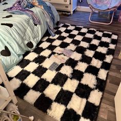 a black and white checkered area rug on the floor next to a child's bed