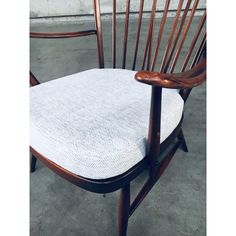 a pair of wooden chairs with white upholstered seat cushions on concrete flooring