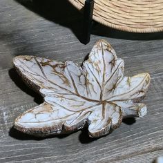 a leaf shaped object sitting on top of a wooden table next to a straw hat