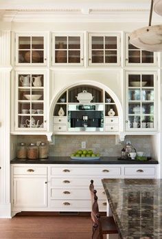 a kitchen with white cabinets and marble counter tops