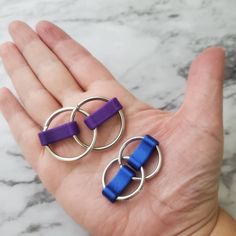 two small purple and blue rings are held in the palm of someone's hand