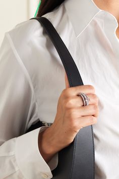 a woman wearing a white shirt and black tie holding a ring in her left hand