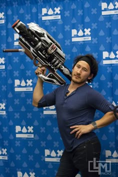 a man holding up a large metal object in front of a blue backdrop