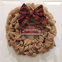 a burlock wreath with a merry christmas sign on it and a bow hanging from the front door