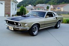 an old mustang is parked in front of a house