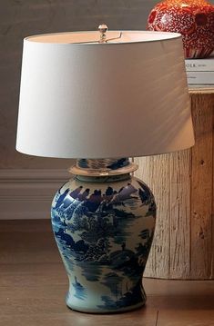 a blue and white vase sitting on top of a wooden table next to a lamp