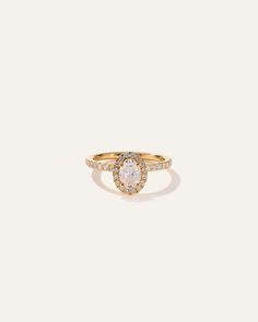 a yellow gold ring with an oval shaped diamond surrounded by small round diamonds on the band