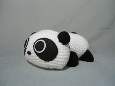 a crocheted panda bear laying on top of a white sheet with black dots