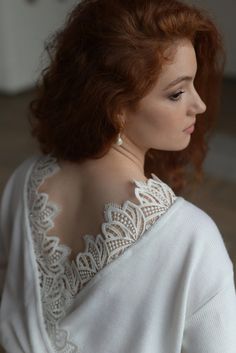 a woman with red hair is wearing a white sweater and has her back turned to the camera