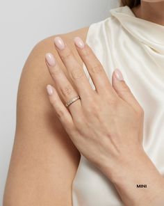 a woman's hand with a diamond ring on her left wrist, wearing a white dress