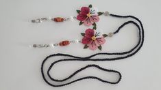 three necklaces with beads and flowers on them sitting on a white surface, one has a pink flower