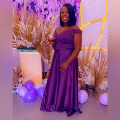 a woman in a purple dress standing next to balloons