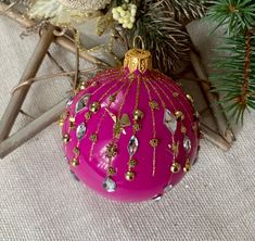 a pink ornament sitting on top of a table next to a christmas tree