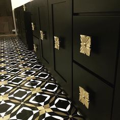 a black and gold tiled floor in a bathroom next to two cabinets with golden knobs