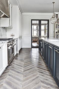 a kitchen with white cabinets and wood flooring next to an open door that leads to another room