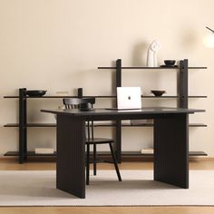 a black desk and chair in front of a book shelf