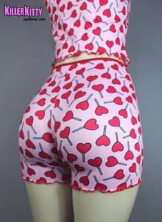 Limited, Custom-made heart lollipop lounge shorts and tank top set. Made in ultra soft knit material with printed lollipop hearts. Top and bottoms are trimmed in red picot elastic with red merrow edging and small rose detail. Also available separately. SHIPPING: Made When Ordered Please allow 5 - 7 DAYS to ship. TANK TOP LENGTH: 12" (armpit to hem) CARE: Delicate cycle, dry low. SHORTS INSEAM: 3" (fits at waist) MODEL: Mannequin has 37" hip VIEW SIZE GUIDE CARE: Delicate cycle, dry low. Playful Red Tops For Loungewear, Pink Heart Print Bottoms For Loungewear, Playful Red Tops For Sleepover, Cute Fitted Tops For Pajama Party, Playful Red Tops For Sleepovers, Pink Fitted Bottoms With Strawberry Print, Fitted Pink Bottoms With Strawberry Print, Cute Fitted Bottoms For Loungewear, Cute Fitted Loungewear Bottoms