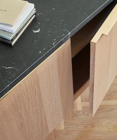 a black counter top sitting next to a wooden cabinet with two books on top of it