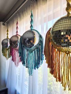 three disco ball chandeliers hanging from the ceiling in front of a window with sheer curtains