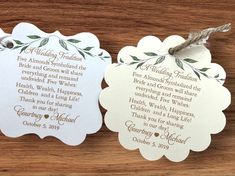 two wedding tags with leaves on them sitting on a wooden table next to each other