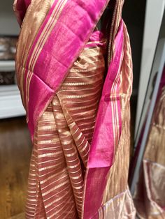 Indulge in ethereal elegance with our exquisite Kora Tissue Silk Saree, featuring a luxurious Katan Silk border adorned with shimmering gold zari. This masterpiece combines the delicate transparency of Kora tissue with the rich texture of Katan silk, creating a captivating contrast. The saree's ethereal beauty is further enhanced by the intricate gold zari work on the border, adding a touch of opulence. Perfect for weddings, cocktail parties, or any special occasion where you desire to make a lasting impression, this saree is a must-have for the discerning woman. Fabric: Kora by Tissue Silk Saree with Katan Silk Border Color: Rose Gold Embellishments: Gold Zari Occasion: Weddings, Parties, Festive Photos don't do justice .. this saree is just... glamorous Comes with fall/ Pico / tassels an Gold Dupatta For Party In Transitional Season, Gold Dupatta For Transitional Party Season, Transitional Gold Raw Silk Traditional Wear, Transitional Gold Traditional Wear In Raw Silk, Transitional Gold Silk Traditional Wear, Festive Gold Silk Traditional Wear, Elegant Tussar Silk Dupatta For Party, Pink Saree For Formal Festivals, Pink Formal Saree For Festivals