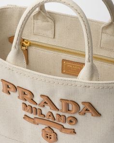 Linen blend handles Removable leather key ring Metal hardware Leather logo on the front and enameled metal triangle logo on the key ring Linen blend interior with double zipper pocket My Prada Is At Home Tote Bag, Luxury Natural Color Tote Bag, Prada Shopping Bag, Prada Canvas Bag, Light Luxury Tote Bag With Gold-tone Hardware, Leather Key Ring, Prada Tote Bag, Large Leather Tote Bag, Embroidered Tote Bag