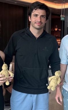 two men and a woman are holding teddy bears in their hands while standing next to each other