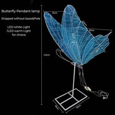 a blue butterfly lamp sitting on top of a metal stand next to a black wall