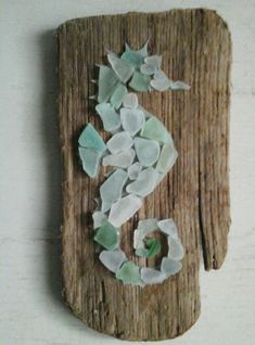 a piece of drift wood with sea glass on it and the number 5 painted on it