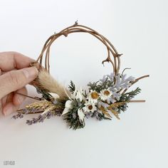 someone is making a flower arrangement out of twigs and dried flowers on a white background