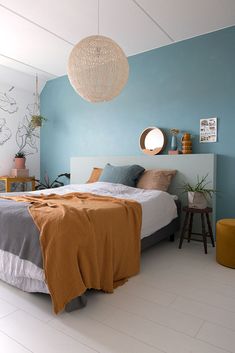 a bedroom with blue walls, white floors and an orange blanket on the headboard