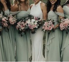 a group of women standing next to each other wearing dresses and holding bouquets in their hands