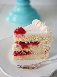 a piece of cake with white frosting and raspberry topping on a plate