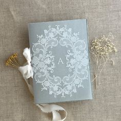 a book with white lace on it next to some flowers