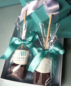 two chocolate candies wrapped in cellophane and tied with blue ribbon, are sitting in a gift box