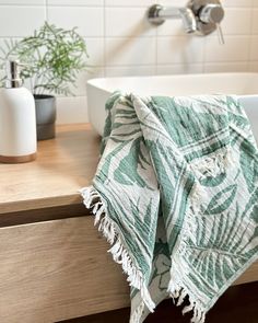 a bathroom sink with a green and white towel on top of it next to a bathtub