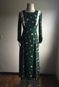 "1970s handmade prairie dress cotton w/lace trim zip up back ties below bust front to back long sleeve w/elastic wrist cuff dark green w/multi-color floral pattern very good vintage condition, light wear no size label tag (measures like xs/s but please go by measurements) measures, lying flat, shoulder-14 1/2\" bust-16 1/2\" waist-14\" hip-22 1/2\" sleeve-23\" length-51\"" Green Lace Trim Dress For Fall, Fitted Long Sleeve Dress With Vintage Print, Green Long Sleeve Cottagecore Dress, Fitted Cottagecore Dress For Fall, Vintage Long Sleeve Green Dress, Long Sleeve Dresses For Vintage Fashion In Spring, Vintage Floral Print Winter Dress, 1970s Green Long Sleeve Dress, 1970s Style Green Long Sleeve Dress