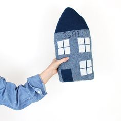 a person holding up a house shaped pillow with the number 2051 on it's side